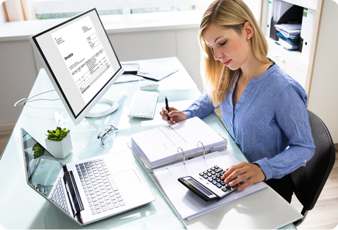 woman at desk using calculator and laptop